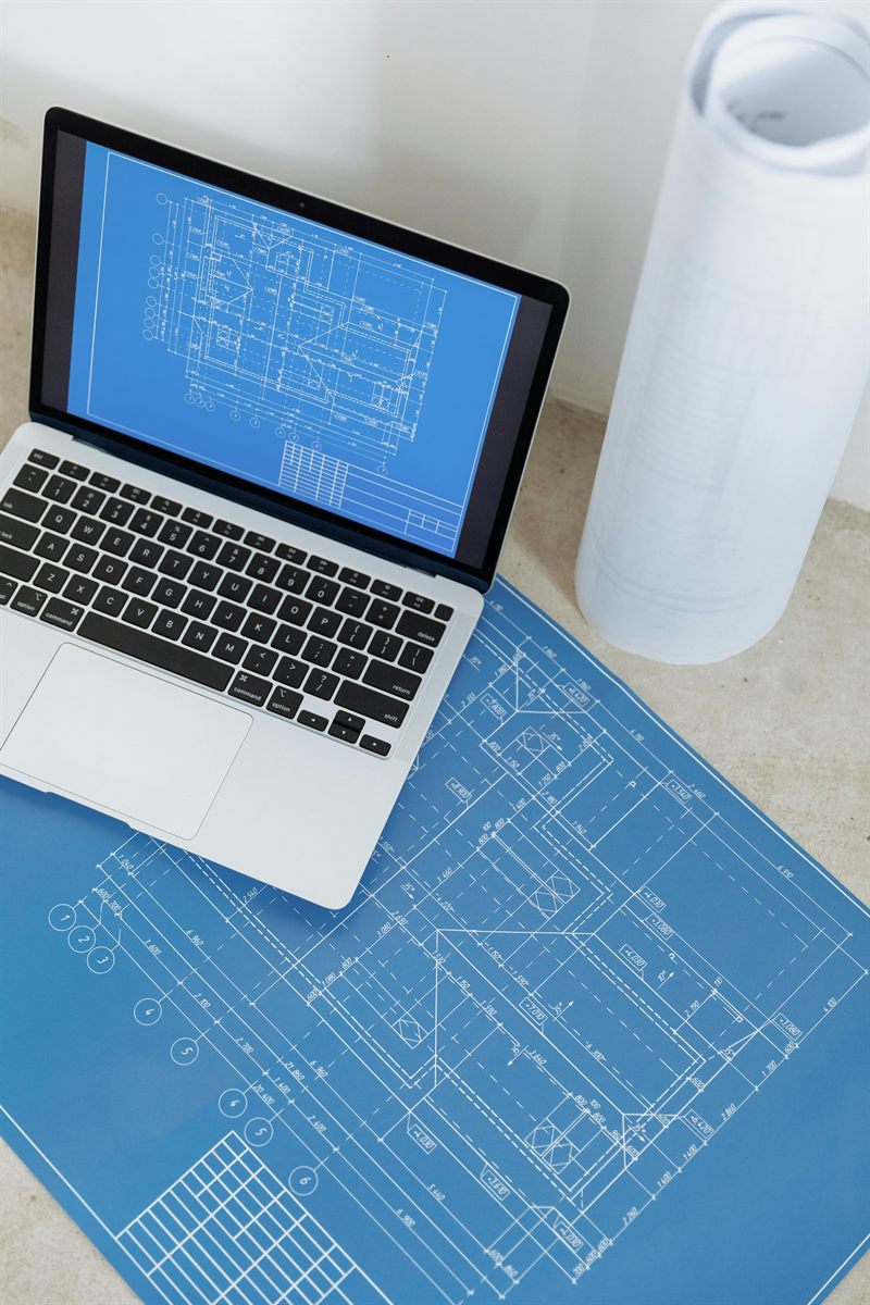 Construction blueprints and digital references arranged for structural drafting review