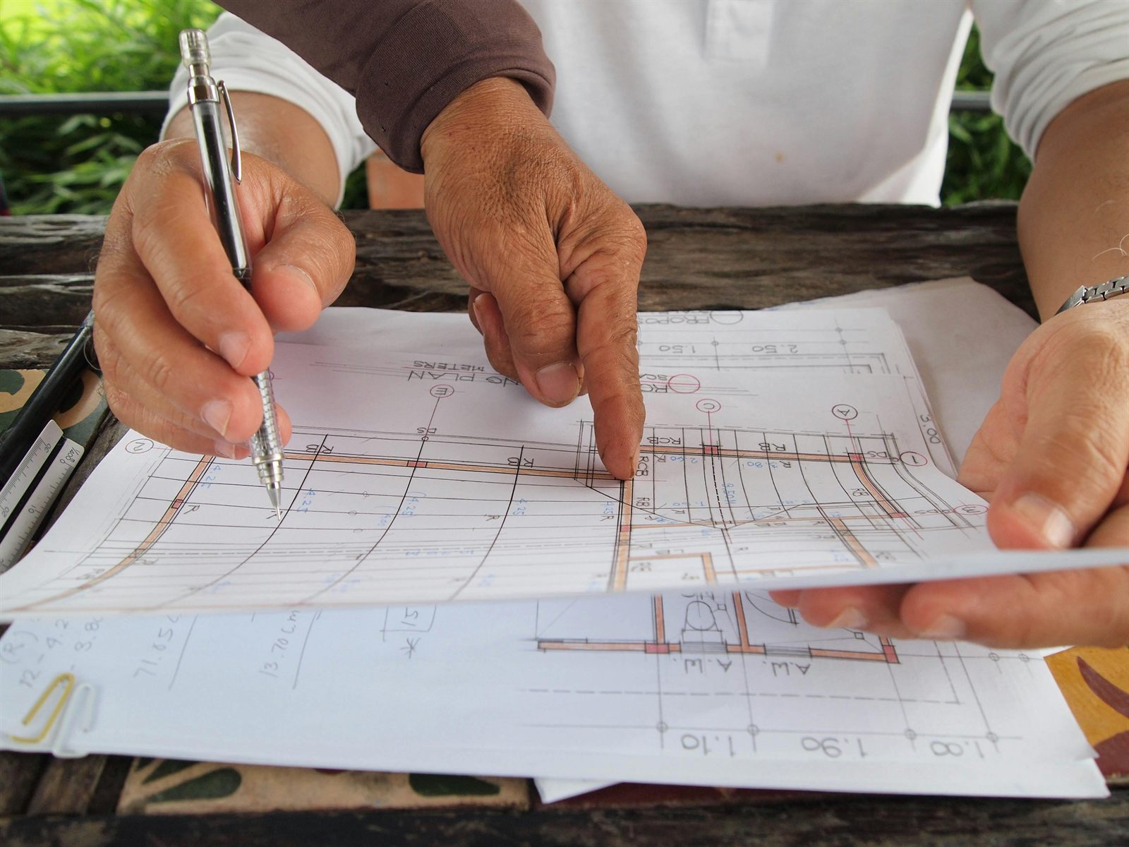 Hands pointing at a site-related blueprint on a desk