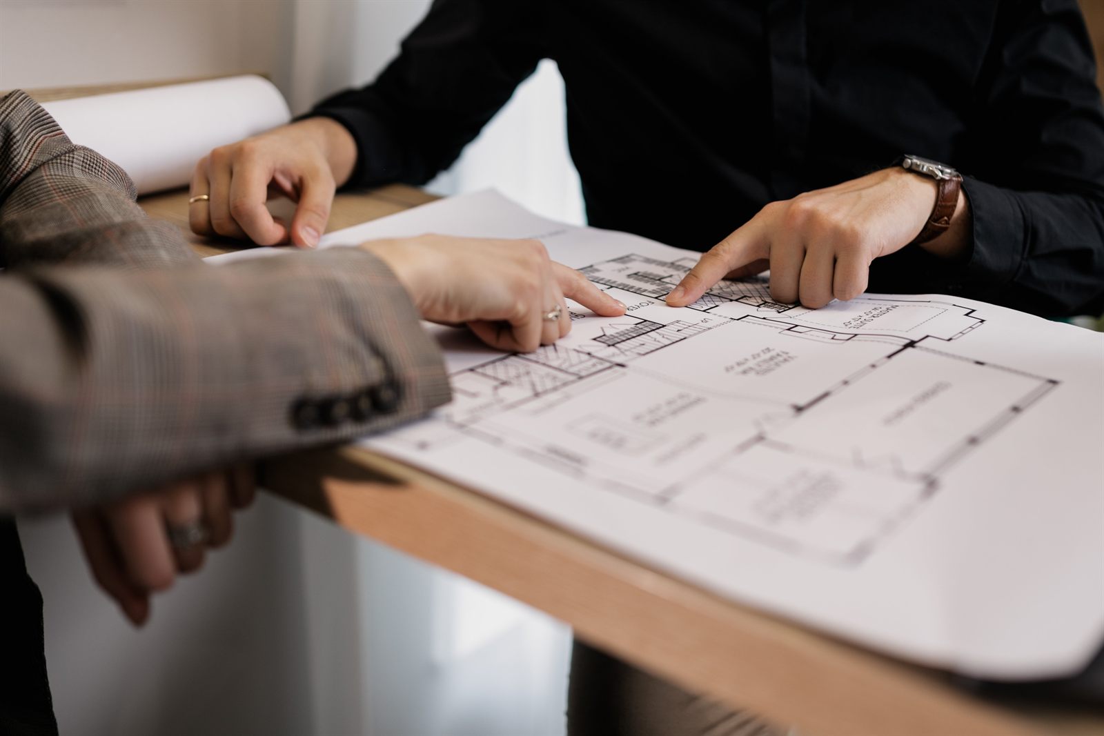 Two people collaborating over a blueprint plan indoors
